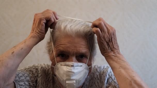 Slow motion porträtt av äldre kvinna sätter på en skyddande respirator. — Stockvideo