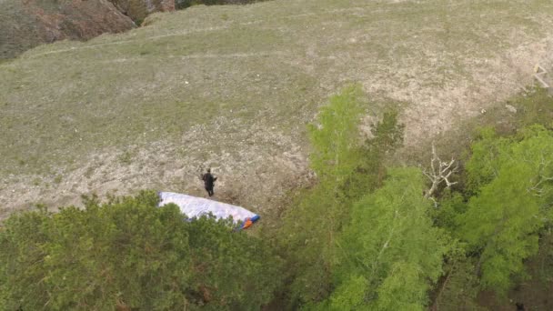 Krasnoïarsk, Russie - 12 mai 2020 : top Vue d'un jeune homme courant et sautant du bord d'un rocher derrière les élingues d'un deltaplane . — Video