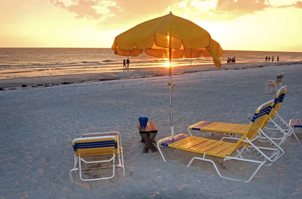 Beach chair and parasol at sunset — Stock Photo, Image