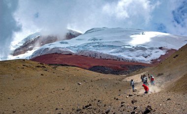 Güneşli ve bulutlu bir öğleden sonra Cotopaxi yanardağının yamaçlarında koşan insanlar. Cotopaxi Ulusal Parkı, Ekvador.