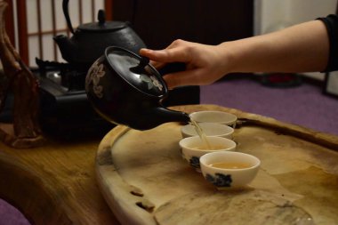 El bardaklara çay dolduruyor.