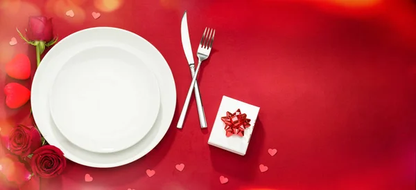 Plate, fork, knife and roses on red cover — ストック写真