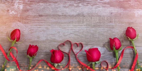 Розы и ленты сердца на старом столе — стоковое фото