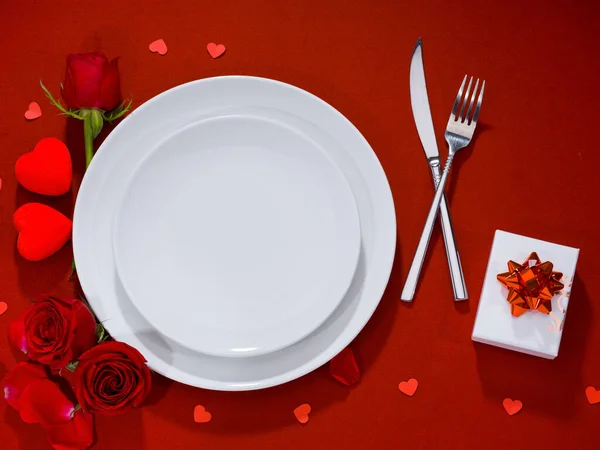 Placa, garfo, faca e caixa de presente com rosas em tecido de veludo — Fotografia de Stock