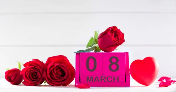 8 Μαρτίου ημερομηνία σε ξύλινο κύβο ημερολόγιο. Τριαντάφυλλα και καρδιά στο τραπέζι — Φωτογραφία Αρχείου