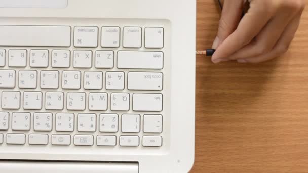 Uma mulher está conectando o conector de áudio do fone de ouvido em um laptop branco — Vídeo de Stock