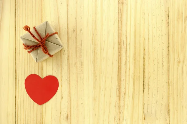 Vista dall'alto della confezione regalo artigianale con cuore su sfondo in legno — Foto Stock