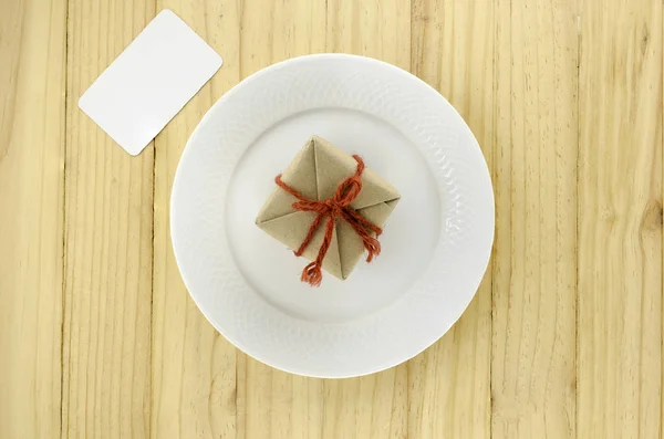 Vista superior de la caja de regalo artesanal en plato sobre fondo de madera — Foto de Stock