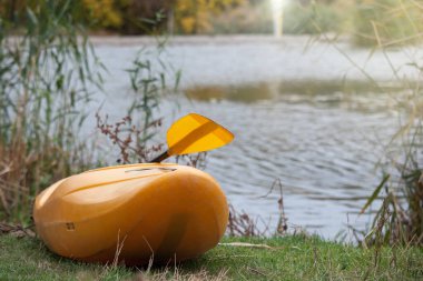 Sarı kano, gölün kıyısında duran kürekle.