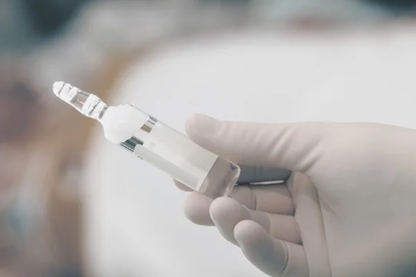 Vial de medicamento en una mano enguantada — Foto de Stock