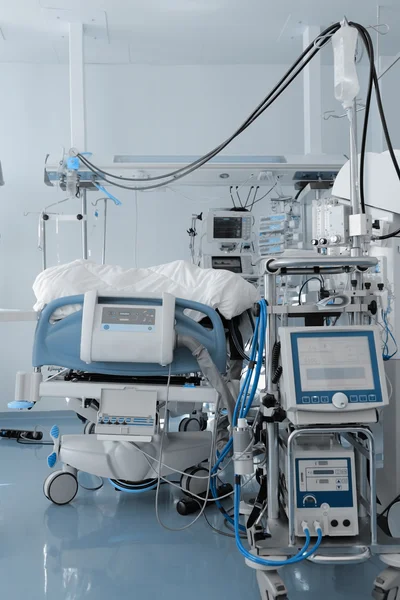 Больничная кровать, окруженная массой медицинского оборудования — стоковое фото