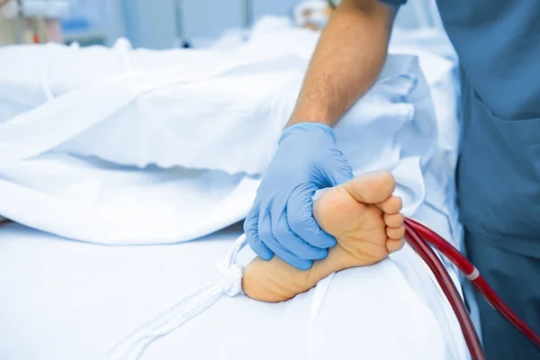 Médico con las manos enguantadas palpando los pies pacientes — Foto de Stock