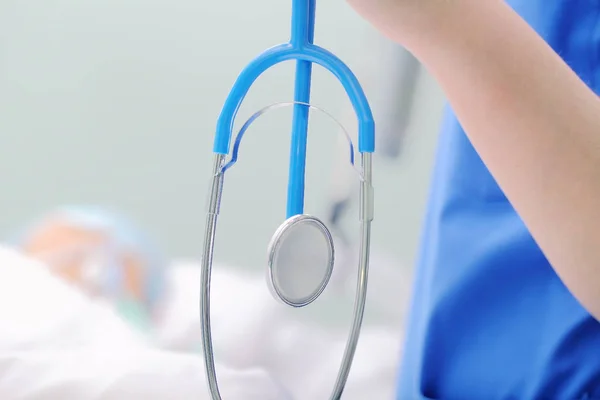 Stéthoscope en main du médecin au chevet du patient — Photo