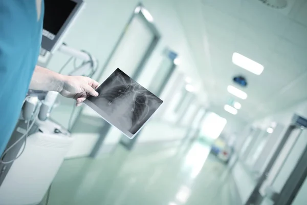 Doctor sosteniendo una imagen de rayos X contra el pasillo del hospital — Foto de Stock