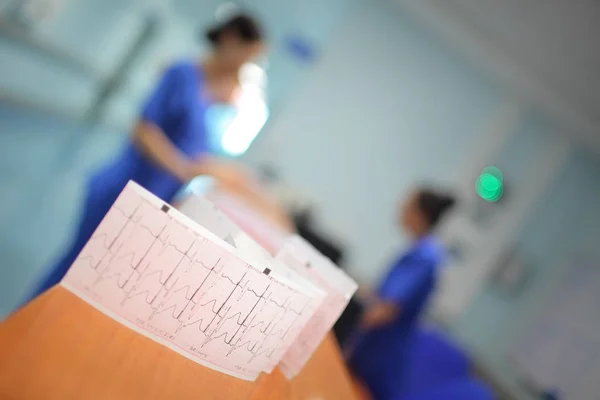 EKG papír na pozadí rozmazané nemocničního života — Stock fotografie