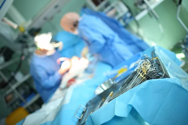 Блюдо хирургических инструментов на фоне работающих врачей — стоковое фото