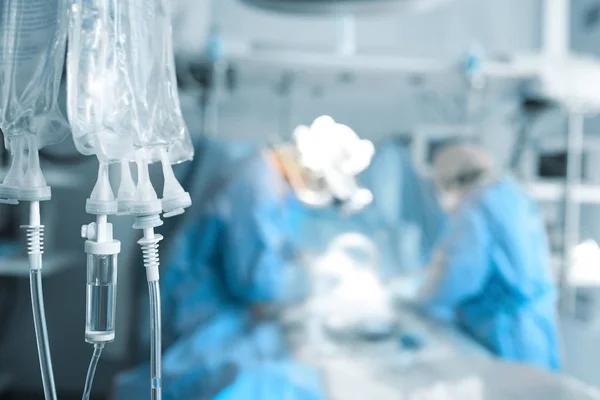 Sistema intravenoso no fundo de cirurgiões operados — Fotografia de Stock