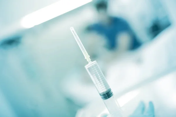 Full syringe on the background of working medical person — Stock Photo, Image