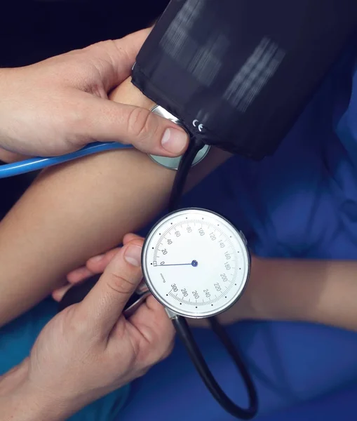 Medical worker measures the blood pressure to the patient in the — Stock Photo, Image