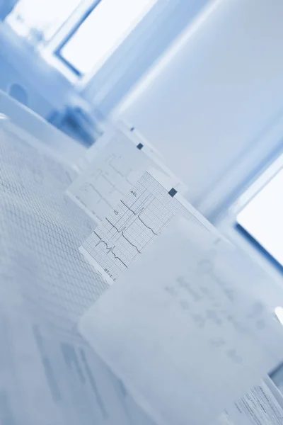 Gebogen Ecg papier op de tafel van de dokter tegen het raam — Stockfoto