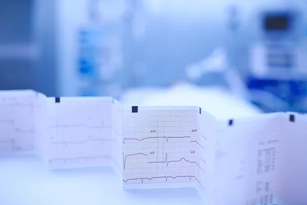 Grafico ECG piegato a fisarmonica sul tavolo dell'infermiera sul backgroun — Foto Stock