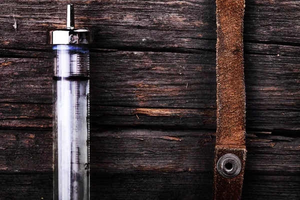 Syringe and suede tourniquet on the rough wooden surface as a co — Stock Photo, Image