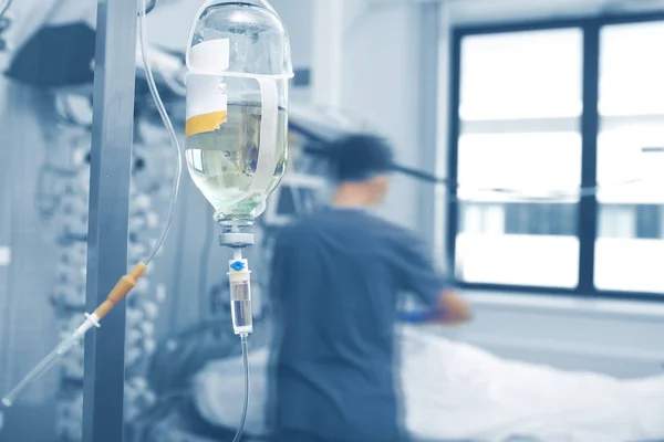 Intravenous infusion bottle hanging on the pole agienst the blur — Stock Photo, Image