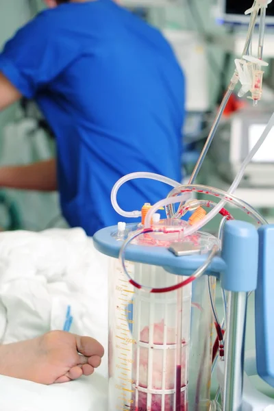 Contenitore di drenaggio del sangue e medico di lavoro vicino al letto del paziente — Foto Stock