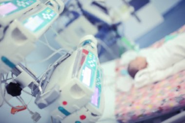 Yeni doğan bebek inten aletleri çevrili yatakta