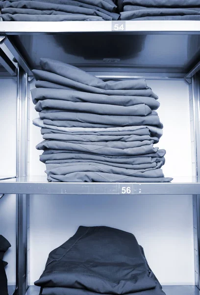 Warehouse shelves with uniform clothes stacked in a pile with si