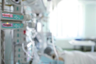 Bilinçsiz hasta yatağında yatarken hastane koğuşunda bulanıklık ve tıbbi geçmiş olarak modern ekipmanlar..