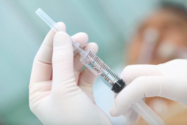 Yatakta yatan hemşirenin eldivenli ellerinde tam şırınga..