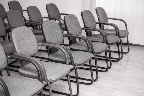 a row of identical empty gray chairs in the audience, a class for meetings and seminars, take the first row