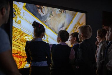 Bir grup çocuk interaktif tarih müzesinde sergiyi ziyaret ediyor, interaktif öğrenim. Çocuklar müzedeki bir sergide interaktif bir dokunmatik ekran kullanıyorlar. St. Petersburg, Rusya, tarihi park, 11.24.2019