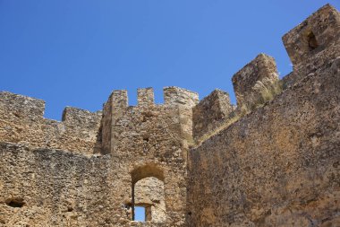 Mavi gökyüzünün arka planında penceresi olan kalenin eski taş duvarları. Güvenlik ve güvenilirlik kavramı.