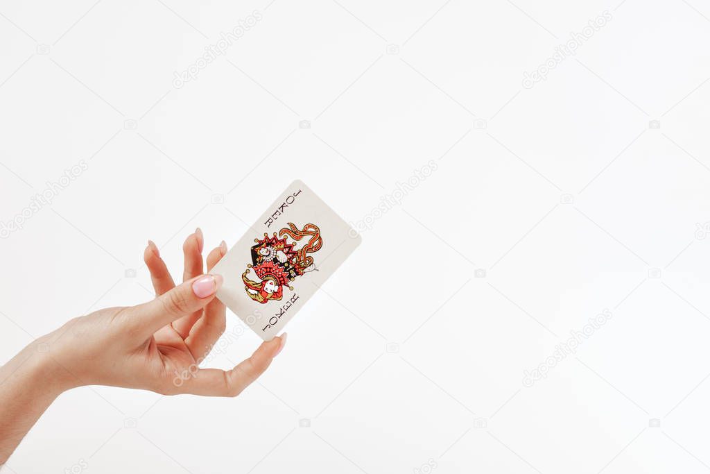 female hand holds a playing card Joker from a card deck of cards on the white background,  concept of good luck, victory, risk
