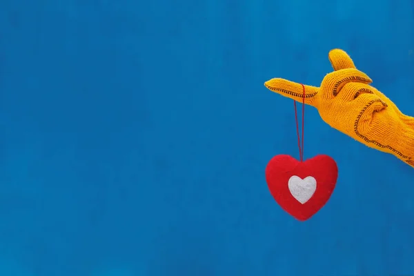 Mão Uma Luva Amarela Mantém Coração Macio Fundo Azul Surpresa — Fotografia de Stock