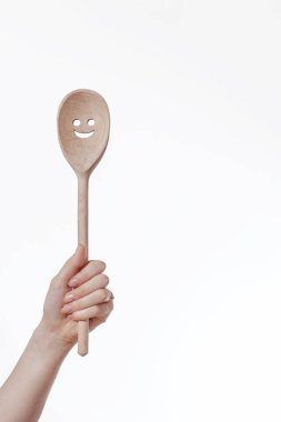 Güzel bir kadın eli beyaz arka planda izole edilmiş ahşap bir spatula kaşığı tutuyor. Yemek yapmak için mutfak aletleri. Hızlı ve lezzetli yemek yapma kavramı.