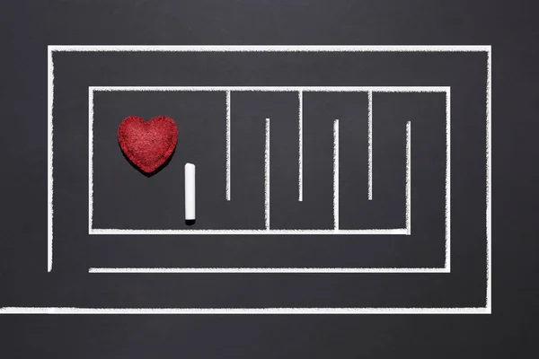 the labyrinth is drawn in chalk on a black chalkboard, the heart is hidden in the center, the concept of finding love, a happy relationship