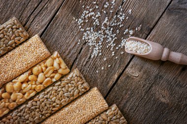 Fıstıklı, susamlı ve ayçiçeği tohumlu karamelli çikolata. Tohumlar, fındıklar ve susam tohumları ile ahşap bir arka planda bal. Şekerli fındık. Balın içinde fındık.