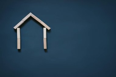 Ahşap bloklardan oluşan mavi bir arka plan, çatı ve duvarlar. Gayrimenkul, ev inşası, sigorta, konut, aile kavramı.