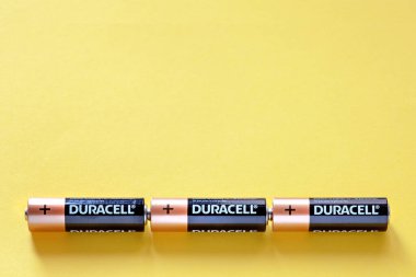 Sarı arkaplandaki Duracell pilleri, kişilerle, arkaplanla, metin için, üst görünüm için birbirine bağlı üç satırdaki piller