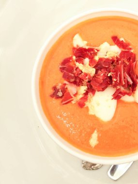 Domuz pastırmalı balkabağı çorbası ve ekmek kaşığıyla beyaz tabakta ekşi krema.