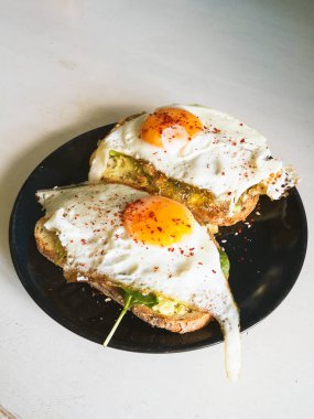 Siyah tabakta yumurta ve ıspanaklı buğday sandviçi, sağlıklı besleyici kahvaltı, diyet yemek. 