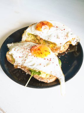 Siyah tabakta yumurta ve ıspanaklı buğday sandviçi, sağlıklı besleyici kahvaltı, diyet yemek. 