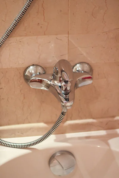 silver metal shiny shower faucet  shower watering can water switch in the hotel home bathroom with  pink tiles on the wall. Bathroom modern luxury interior.