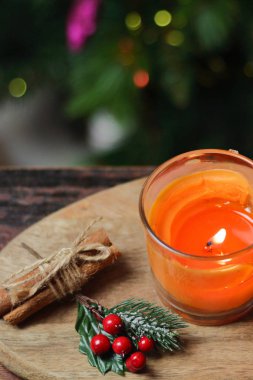 Ahşap bir standın üzerinde Noel portakallı bir mum, bir tutam tarçın, ökseotu ve oyuncaklarla süslenmiş bir Noel ağacı. Noel Yeni Yıl Akşam Havası, Tebrik Kartı