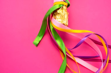 Şampanya şişesi boynu altın folyoyla ve parlak pembe arka planda renkli saten kurdeleler düz manzaralı. Kutlama ve kutlama kavramı, doğum günü, tebrikler, mutluluk, parti 