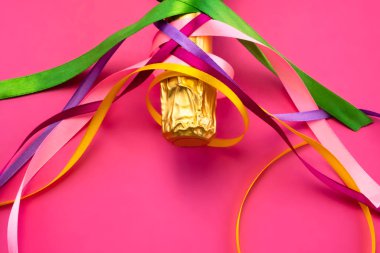 Şampanya şişesi boynu altın folyoyla ve parlak pembe arka planda renkli saten kurdeleler düz manzaralı. Kutlama ve kutlama kavramı, doğum günü, tebrikler, mutluluk, parti 