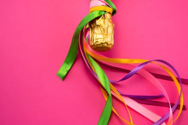 Şampanya şişesi boynu altın folyoyla ve parlak pembe arka planda renkli saten kurdeleler düz manzaralı. Kutlama ve kutlama kavramı, doğum günü, tebrikler, mutluluk, parti 